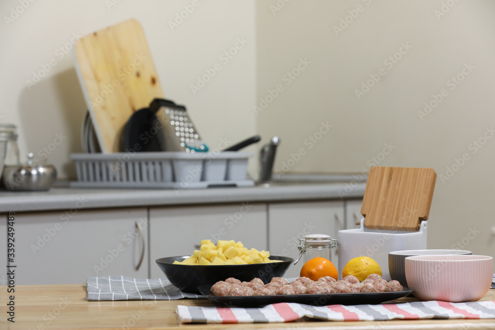 Fresh peeled potato, carrot, lemon and meat balls on a kitchen table. Preparing for cooking. Fresh peeled potato, carrot, lemon and meat balls on a kitchen table. Preparing for cooking.