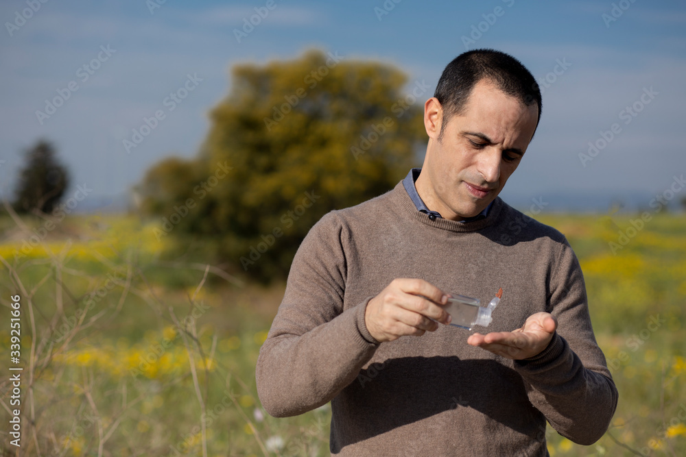 Uomo utilizza un detergente per disinfettare le mani , isolata su sfondo natura Uomo utilizza un detergente per disinfettare le mani , isolata su sfondo natura