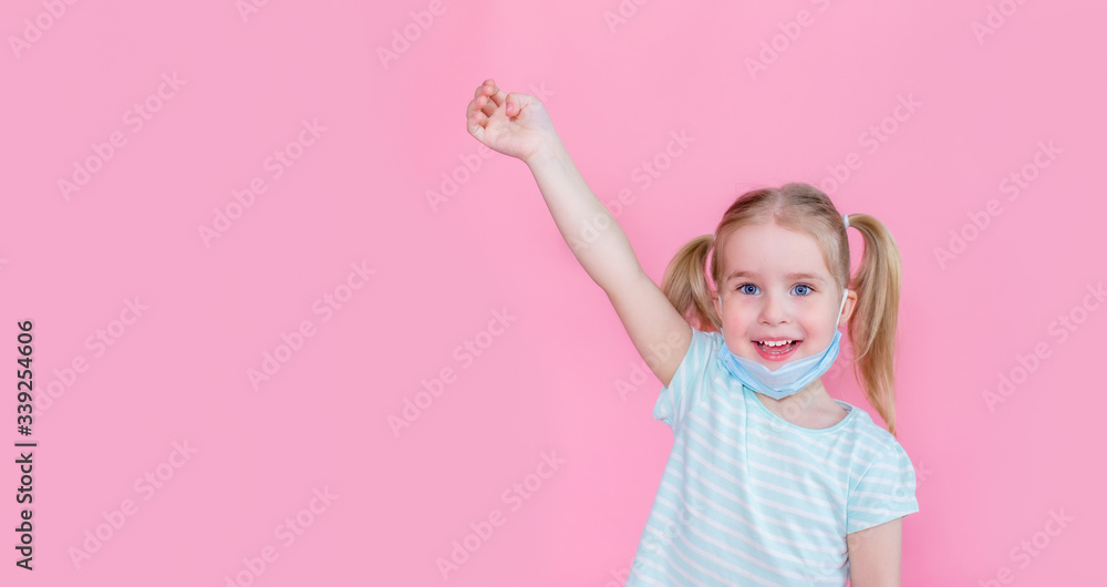 Optimistic, smiling happy little girl taking off the medical mask from face on a pink background with hand up showing end of the pandemia. Copyspace. Optimistic, smiling happy little girl taking off the medical mask from face on a pink background with hand up showing end of the pandemia. Copyspace.
