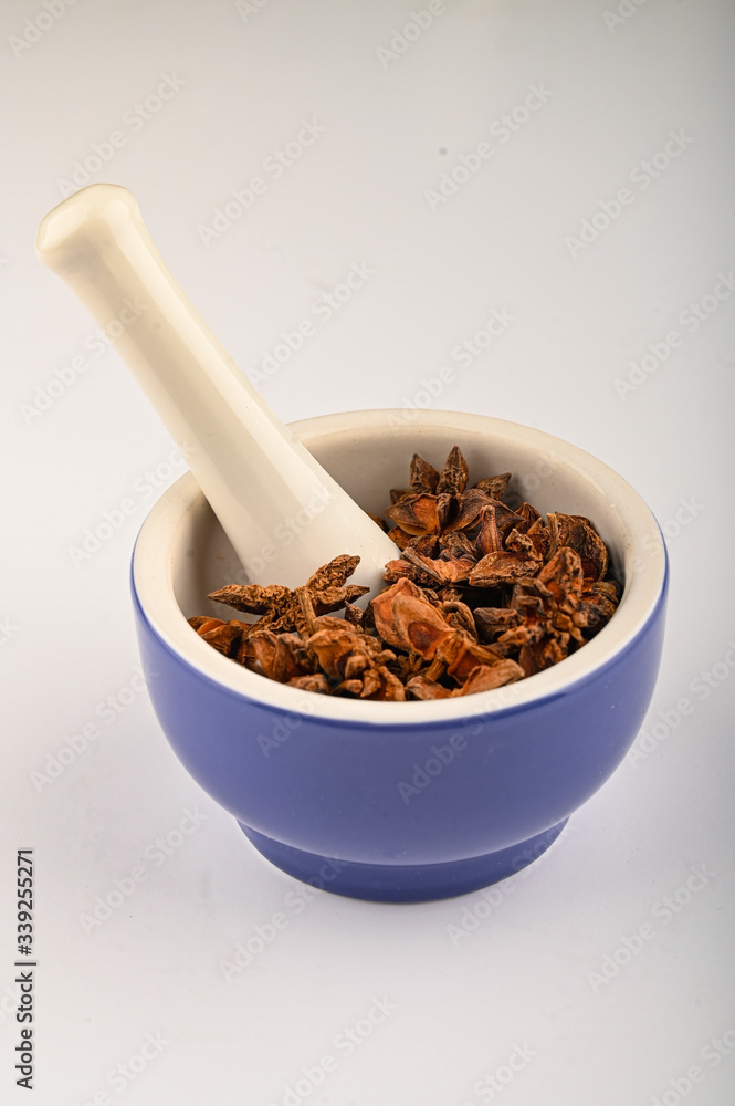 star anise in a blue ceramic spice mortar with a pestle on a white background. Close up. star anise in a blue ceramic spice mortar with a pestle on a white background. Close up.