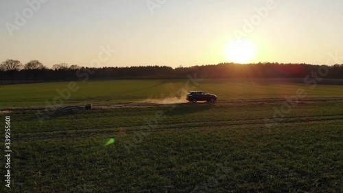 Schwarzes Auto SUV auf Feldweg voller Staub beim Sonnenuntergang während der Corona Pandemie