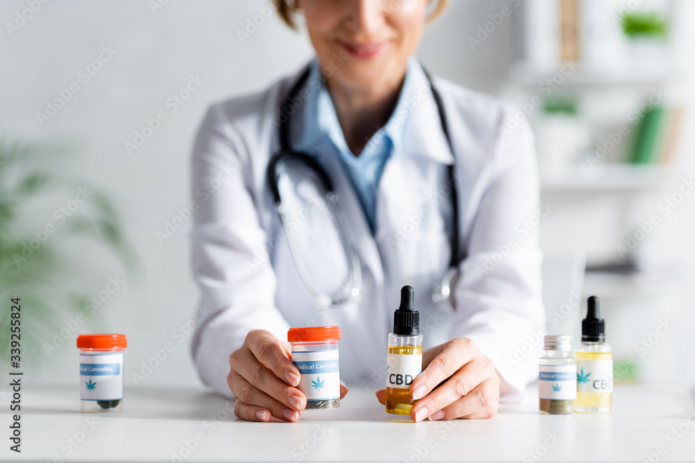 cropped view of doctor in white coat holding bottles with cbd and medical cannabis lettering cropped view of doctor in white coat holding bottles with cbd and medical cannabis lettering