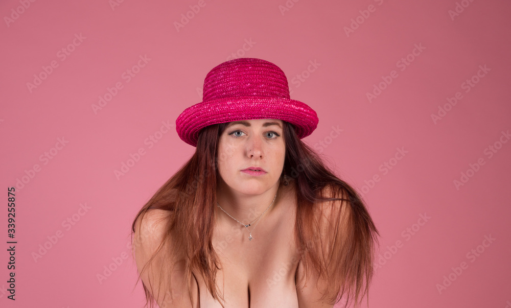 Redhead with striking blue eyes on a pink background with a pink hat Redhead with striking blue eyes on a pink background with a pink hat