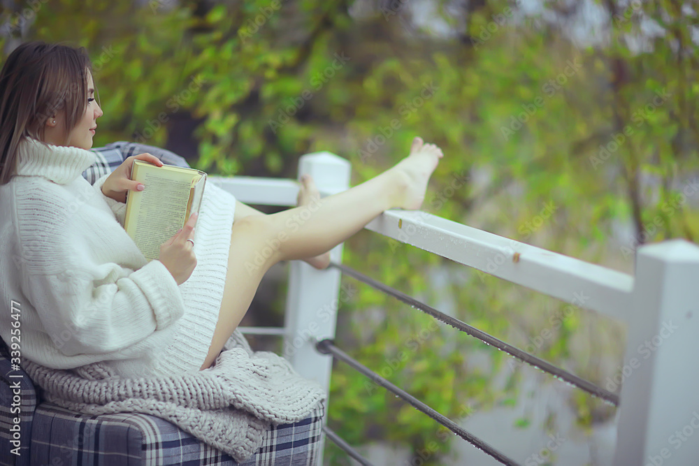 Naklejka premium green trees book girl spring, young beautiful girl reads a book on the veranda seasonal look