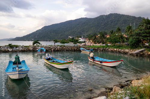 Traditional fishing boats at the pier of Koh Phangan island in Thailand at sunset on a cloudy day.