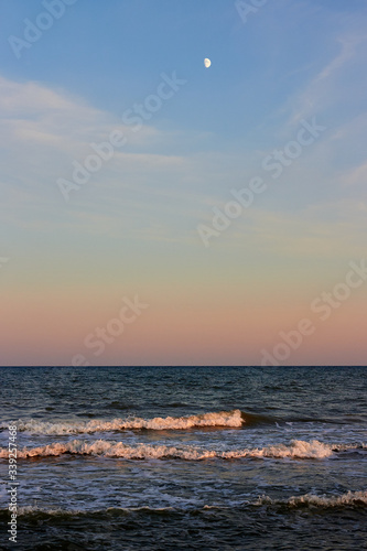 Сoast of the sea and waves with the moon at twilight sunset