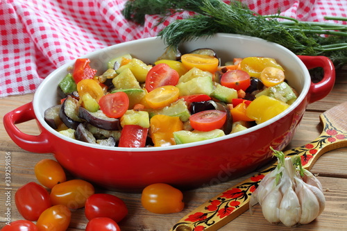 Vegetable stew with eggplant and zucchini on a wooden background