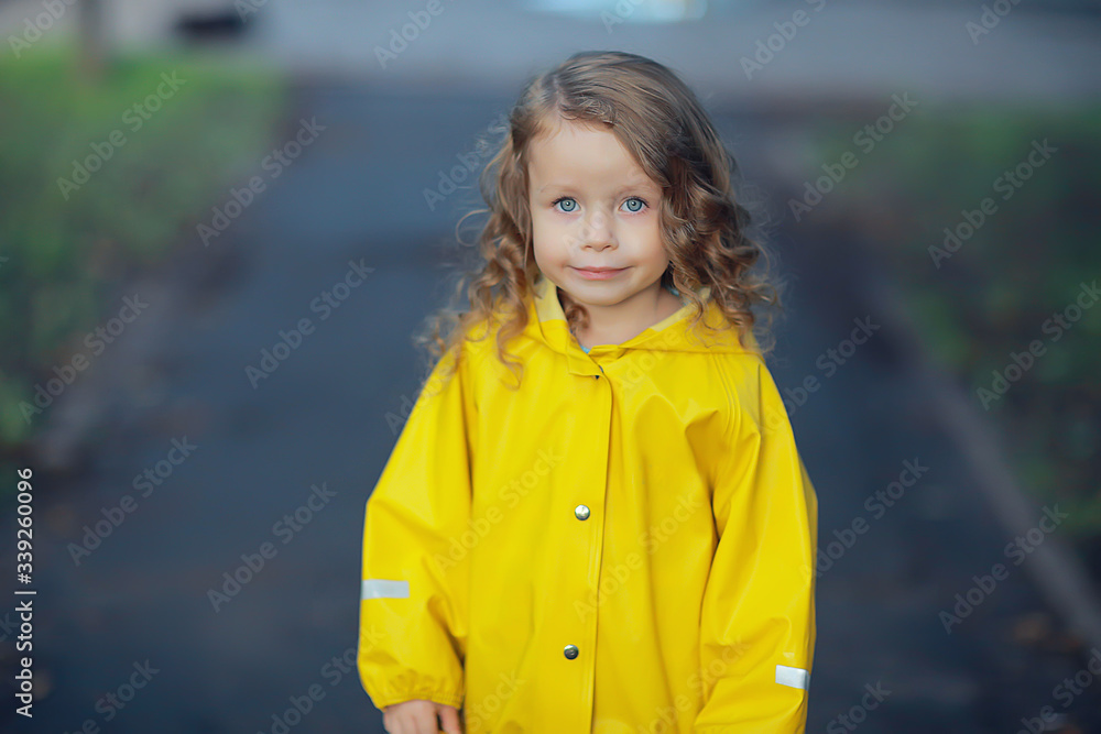 little girl in a yellow raincoat / portrait of a child in autumn clothes, a walk in the rain little girl in a yellow raincoat / portrait of a child in autumn clothes, a walk in the rain