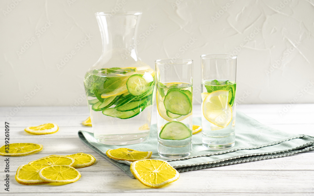 Light and fresh cucumber, lemon beverage on white table with lemon slices Drink for weight loss and lower blood pressure