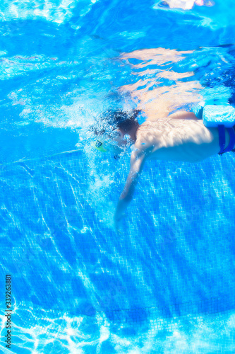 Young boy swimming in swimming pool, underwater view.