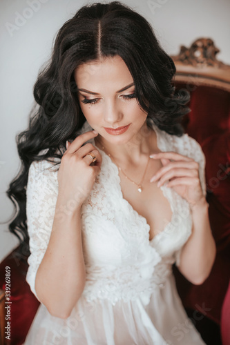 Beautiful brunette bride with stylish make-up in white underwear.Morning bride