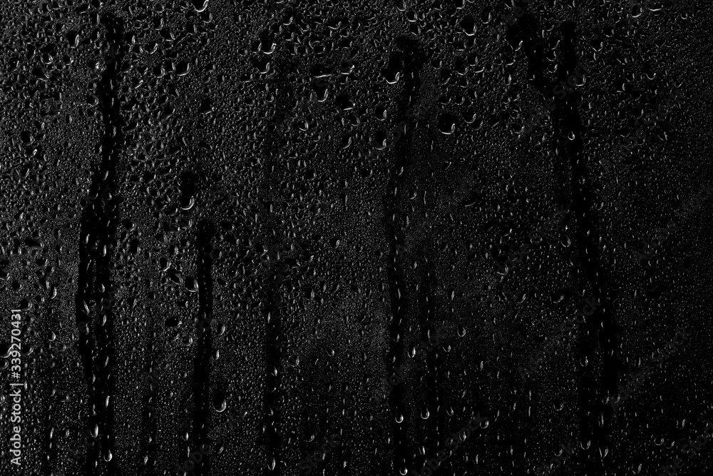 Drops of water flow down the surface of the clear glass on a black background.	 - obrazy, fototapety, plakaty 