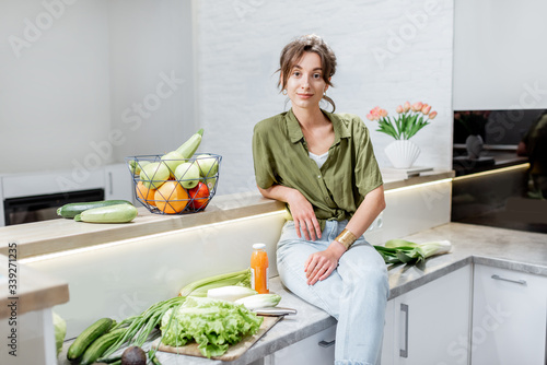 Portrait of a young and cheerful woman with healthy raw food on the kitchen at home. Vegetarianism  wellbeing and healthy lifestyle concept