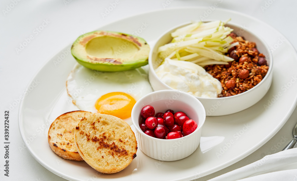Homemade granola with sliced apples and yogurt, sunny side up, grilled avocado and berries Homemade granola with sliced apples and yogurt, sunny side up, grilled avocado and berries