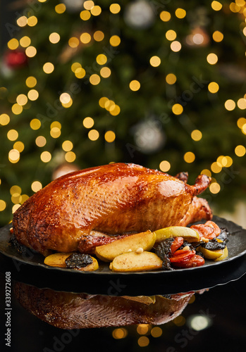 Roasted whole duck with apples, dried fruits and pine nuts served on black dish