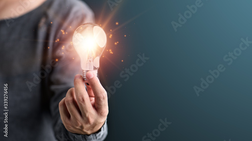 Hand of man holding illuminated light bulb, idea, innovation and inspiration concept.concept creativity with bulbs that shine glitter.