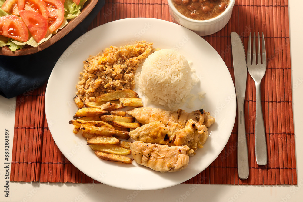 Dish of grilled chicken fillet with rice, beans, french fries and farofa on white plate. Top view. Dish of grilled chicken fillet with rice, beans, french fries and farofa on white plate. Top view.
