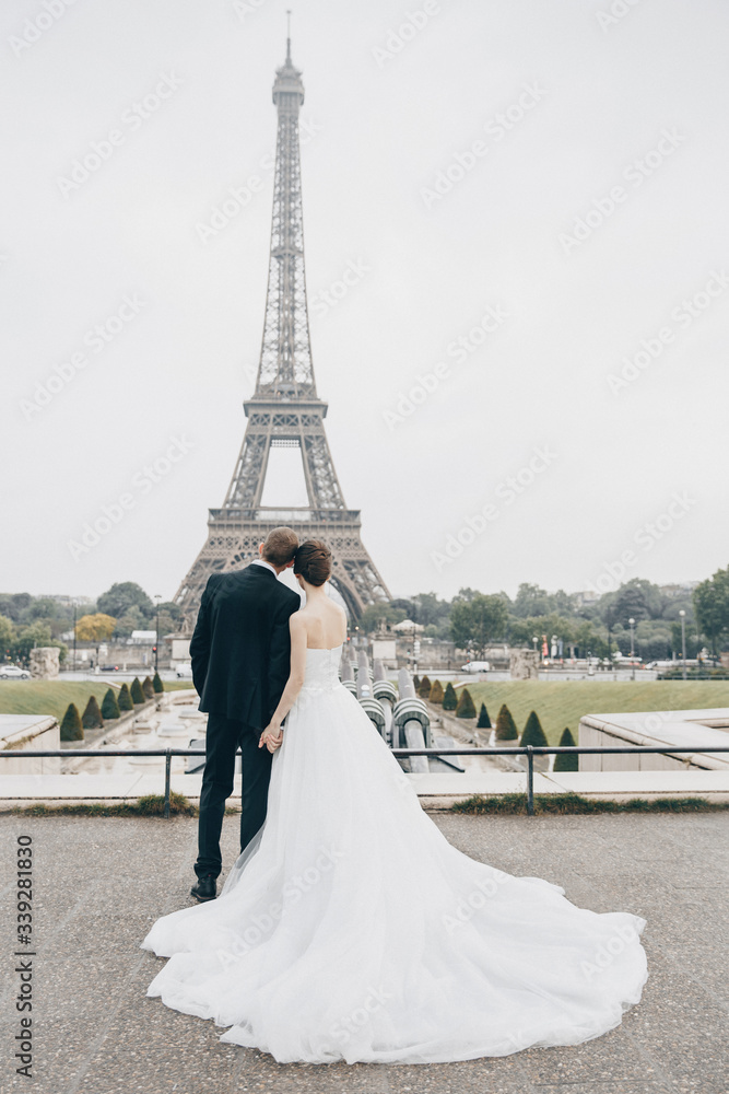 Bride and groom having a romantic marriage in Paris. Wedding couple on a background of Eiffel Tower in Paris. Romantic date, wedding ceremony in France. Bride in wedding dress. Wedding ring