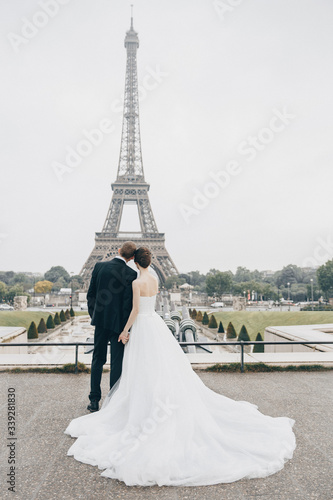 Bride and groom having a romantic marriage in Paris. Wedding couple on a background of Eiffel Tower in Paris. Romantic date, wedding ceremony in France. Bride in wedding dress. Wedding ring © Maksim