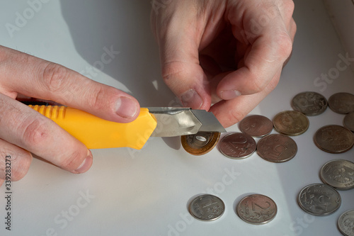 A man counts money and divides it. Round coins. Cutting of money with a knife
