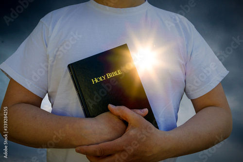 Man holding a Bible with glowing heart sun