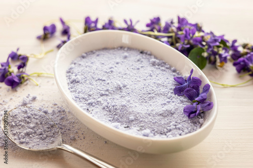 viola violeta odorata violet natural sugar bath salt on white background in porcelain dish 