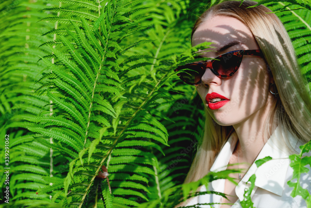Spectacular bright portrait of a beautiful girl with a fern branch near her face. The concept of natural beauty and unity with nature Spectacular bright portrait of a beautiful girl with a fern branch near her face. The concept of natural beauty and unity with nature