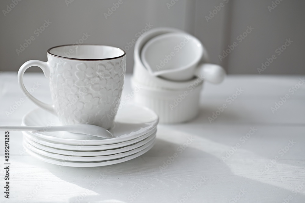 white tea cup, plates and saucer on a shelf. minimal style tableware. trendy uncluttered kitchen. elegant modern monochrome design. white tea cup, plates and saucer on a shelf. minimal style tableware. trendy uncluttered kitchen. elegant modern monochrome design.