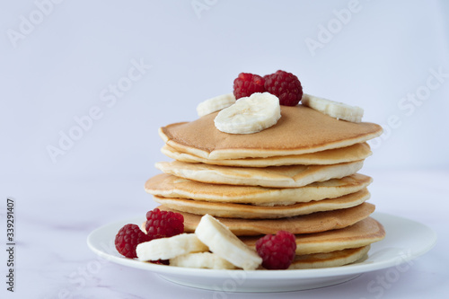 breakfast, pancakes with raspberry and banana on a white plate