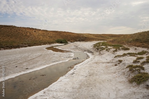 Salty creek with white salty shores. In the vicinity of the salt lake Baskunchak, Bogdo-Baskunchak Nature Reserve, Astrakhan region, Russia.