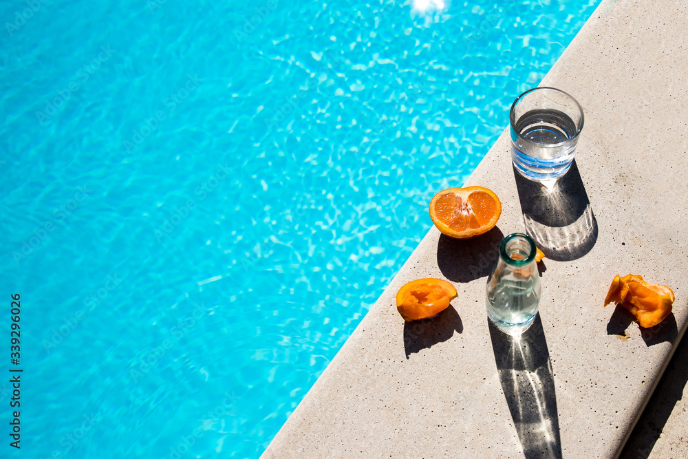 glasses and fruits next to the pool