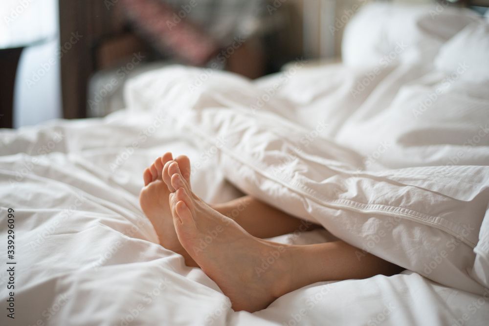 Female feet peeking out from white blanket Female feet peeking out from white blanket