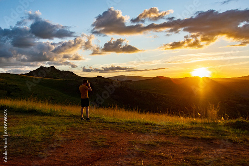 Man is making a photo of a nice sunset in the mountains of Swaziland with beautiful yellow and orange colors in the sky