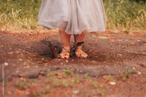 Outdoor summer picture of little girl in a grey skirt jumping in a puddle