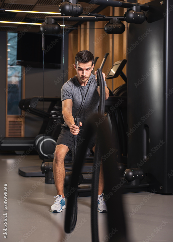 Young fit man working out with battle ropes at gym Young fit man working out with battle ropes at gym