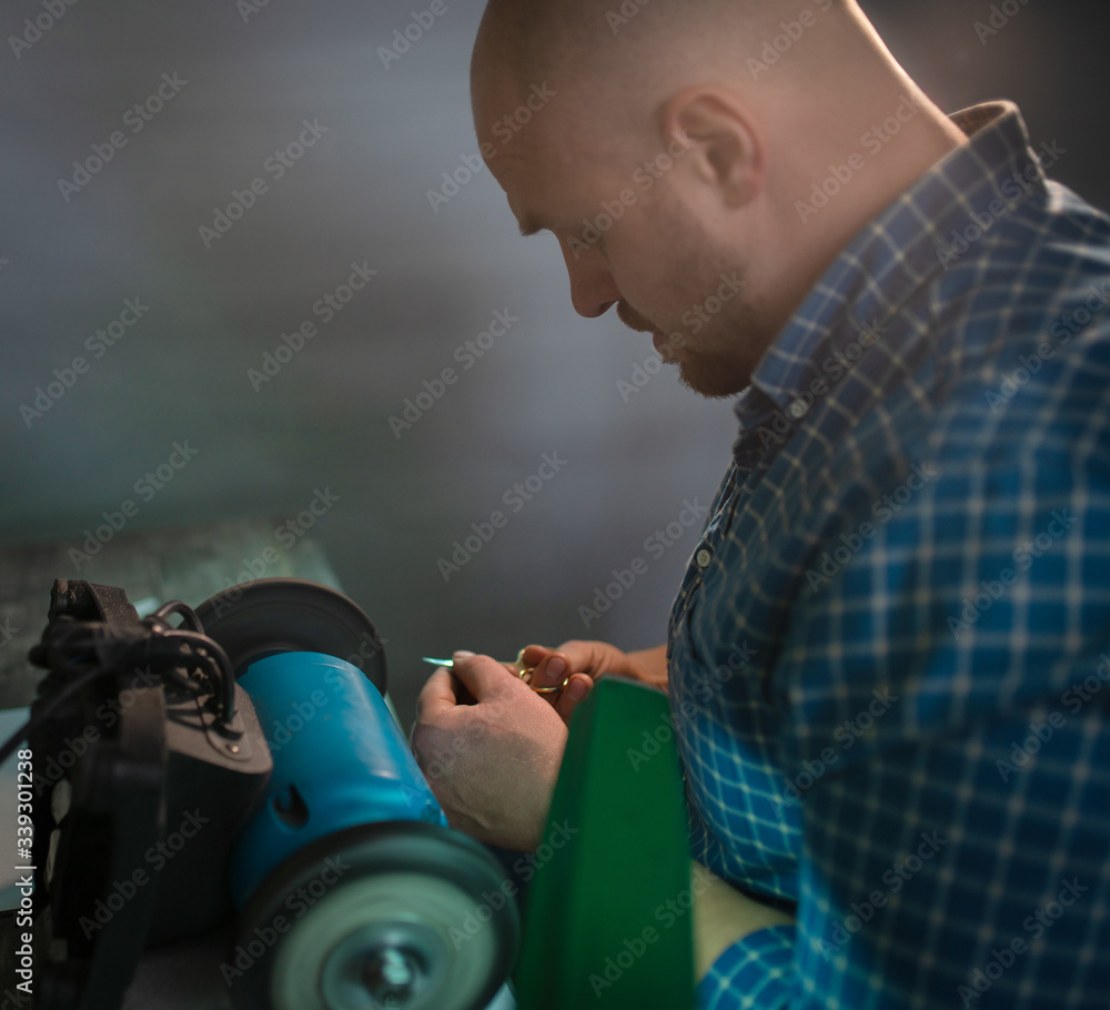 Naklejka premium Master sharpens scissors on special equipment for sharpening tool