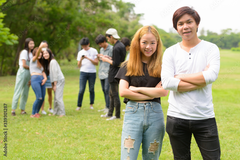 Happy young Asian couple together with friends at the park