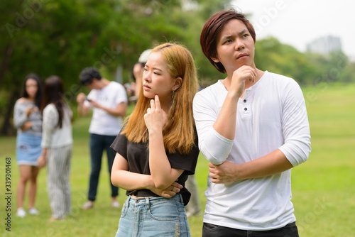 Young Asian couple thinking together with friends at the park © Ranta Images