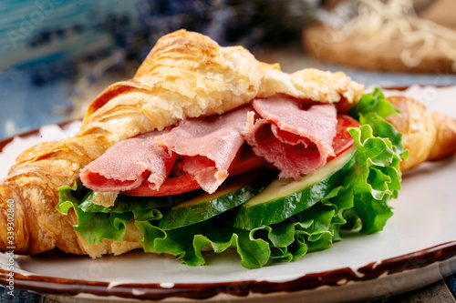 Croissant with ham and vegetables on a plate. Breakfast. Closeup