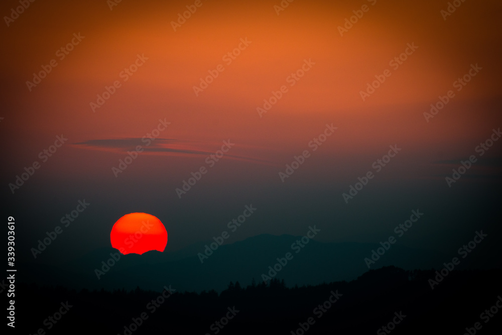 Obraz premium Sunset with disappearing sun over mountains
