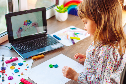 Little girl molding colorful clay cloud watching online learning lesson