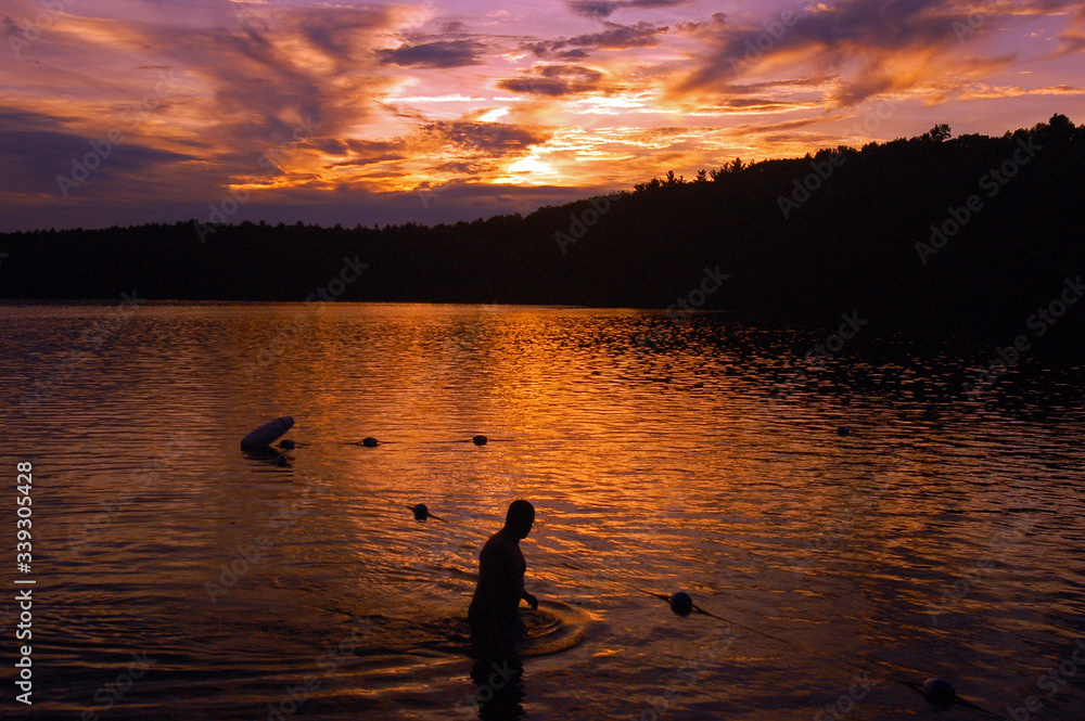 Fototapeta premium A Swimmer Emerges from Walden Pond, Massachusetts at Sunset
