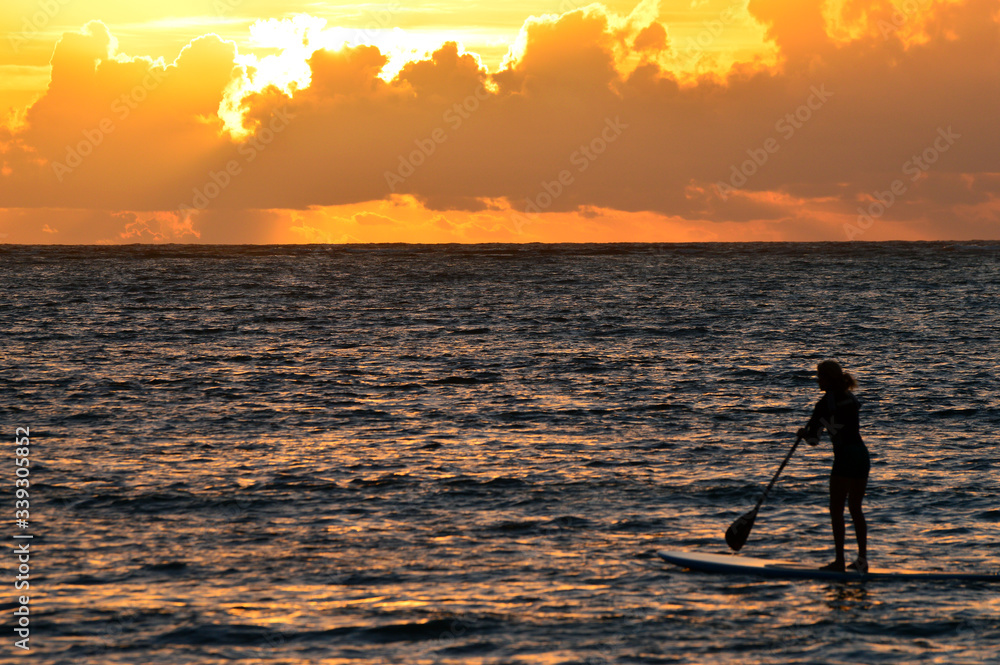 A Paddleboarder heads into the ocean to greet the Sunrise