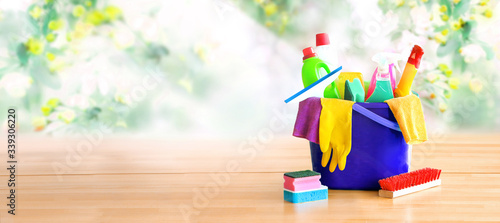 Basket with cleaning items on blurry spring background. Washing set with copy space banner.