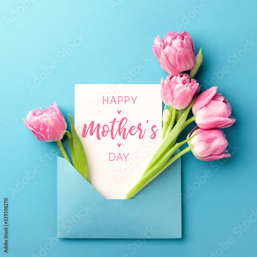 Bouquet of pink tulips in turquoise envelope on turquoise background. Happy Mother's Day greeting card. Flat lay, top view. © Olga Zarytska