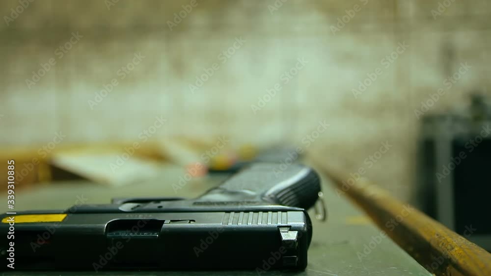 Man picked up a 9mm pistol and shoots in shooting range. More men in the blur background. Close up, selective focus and copy space. Man picked up a 9mm pistol and shoots in shooting range. More men in the blur background. Close up, selective focus and copy space.