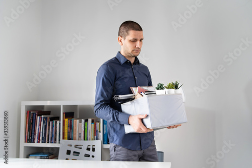 Portrait of adult caucasian man businessman wearing shirt holding a box personal items stuff leaving the office being fired from work due recession economic crisis downturn losing job company shutdown photo