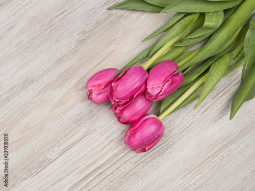 Bouquet of pink tulips on wooden background. The holiday gift.