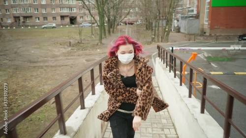 Concept: urban healthcare during pollution pandemic. Beautiful young asian girl with colored hair in medical mask wearing grunge fashion clothing walk street