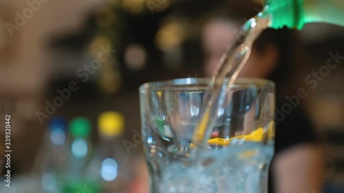 Pouring sparkling water from a bottle to a glass. Close up and copy space.